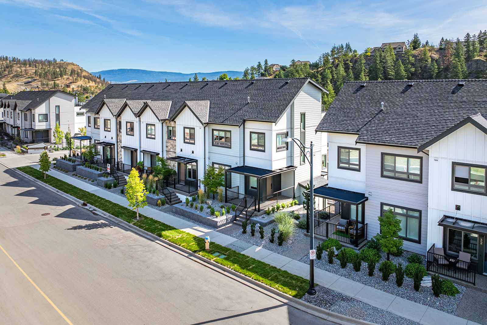 Aerial street view of Juniper townhomes in Wilden, Kelowna with hillside and forest backdrop